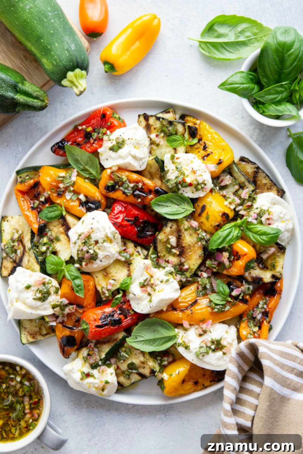 Smoky Grilled Vegetables, Creamy Burrata, Zesty Chimichurri 3 Close-up of grilled zucchini and bell peppers topped with melting burrata and green chimichurri sauce.