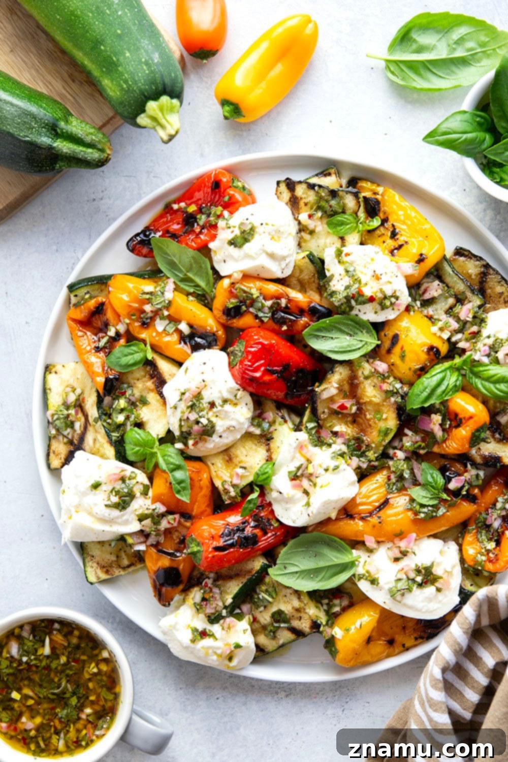 Smoky Grilled Vegetables, Creamy Burrata, Zesty Chimichurri 6 A vibrant platter featuring grilled zucchini and sweet peppers, burrata, and fresh chimichurri, ready for serving.