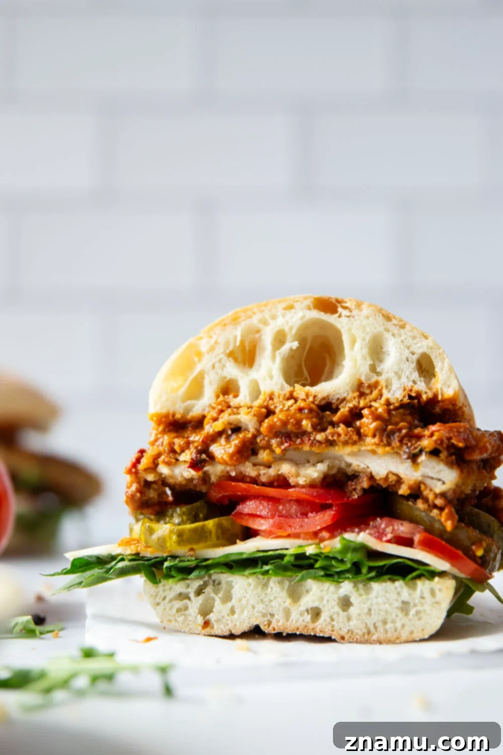 Romesco Chicken Crunch Sandwich 5 A beautifully assembled Crispy Chicken Romesco Sandwich ready to be served, highlighting the layers of crispy chicken, romesco sauce, cheese, and fresh ingredients.