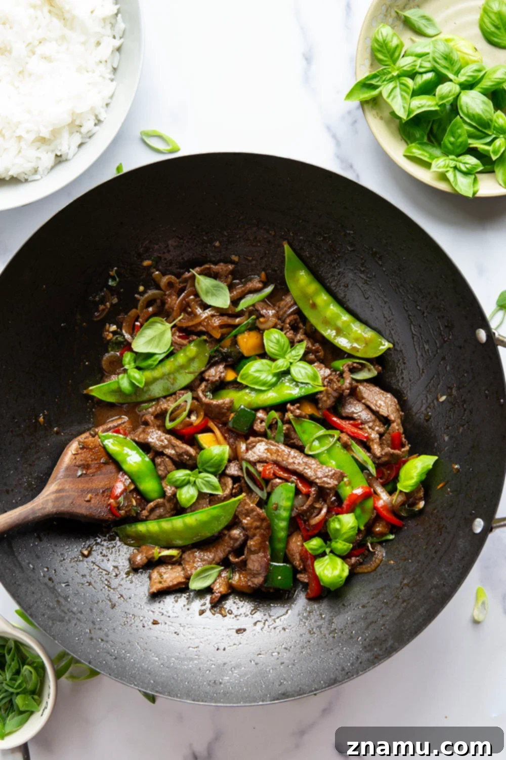 Wok-Fired Thai Basil Beef 2 This Thai basil beef stir fry features juicy seared steak strips in a savory sauce with lots of tender vegetables and fresh basil.