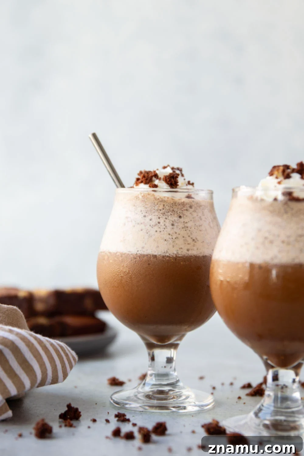 Fudgy Mocha Freeze 2 Decadent homemade Brownie Mocha Frappuccino, topped with whipped cream and brownie crumbles, in a tall glass