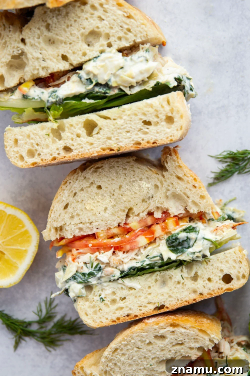 A final hero shot of the spinach artichoke chicken sandwich, cut in half to reveal its mouth-watering layers.