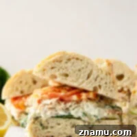 This spinach artichoke chicken sandwich features tender shredded chicken, creamy homemade spinach artichoke spread, and juicy tomato slices sandwiched between soft ciabatta bread.