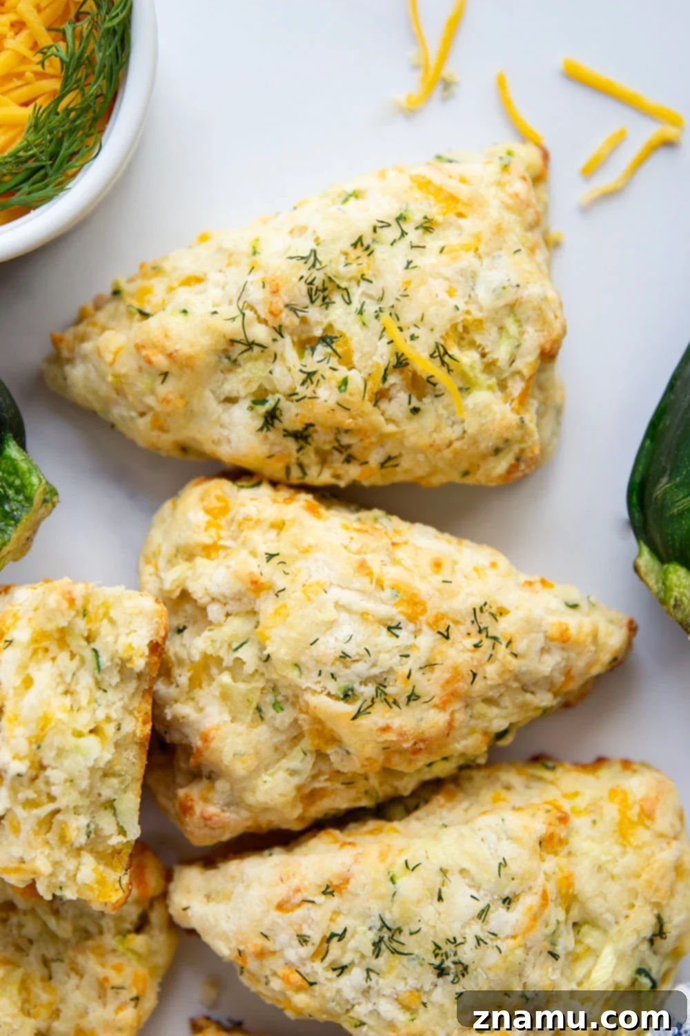 Bright Dill Cheddar Zucchini Scones 3 A stack of golden brown cheddar dill zucchini scones, highlighting their rustic texture and cheesy goodness.