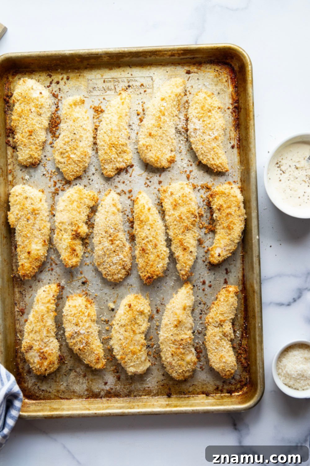 Uncooked chicken tenders coated in black pepper asiago breading