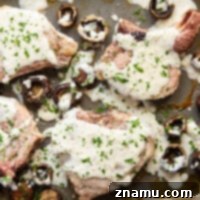 These garlic Parmesan pork chops are roasted entirely on one sheet pan alongside tender mushrooms with a creamy garlic Parmesan sauce spooned on top.