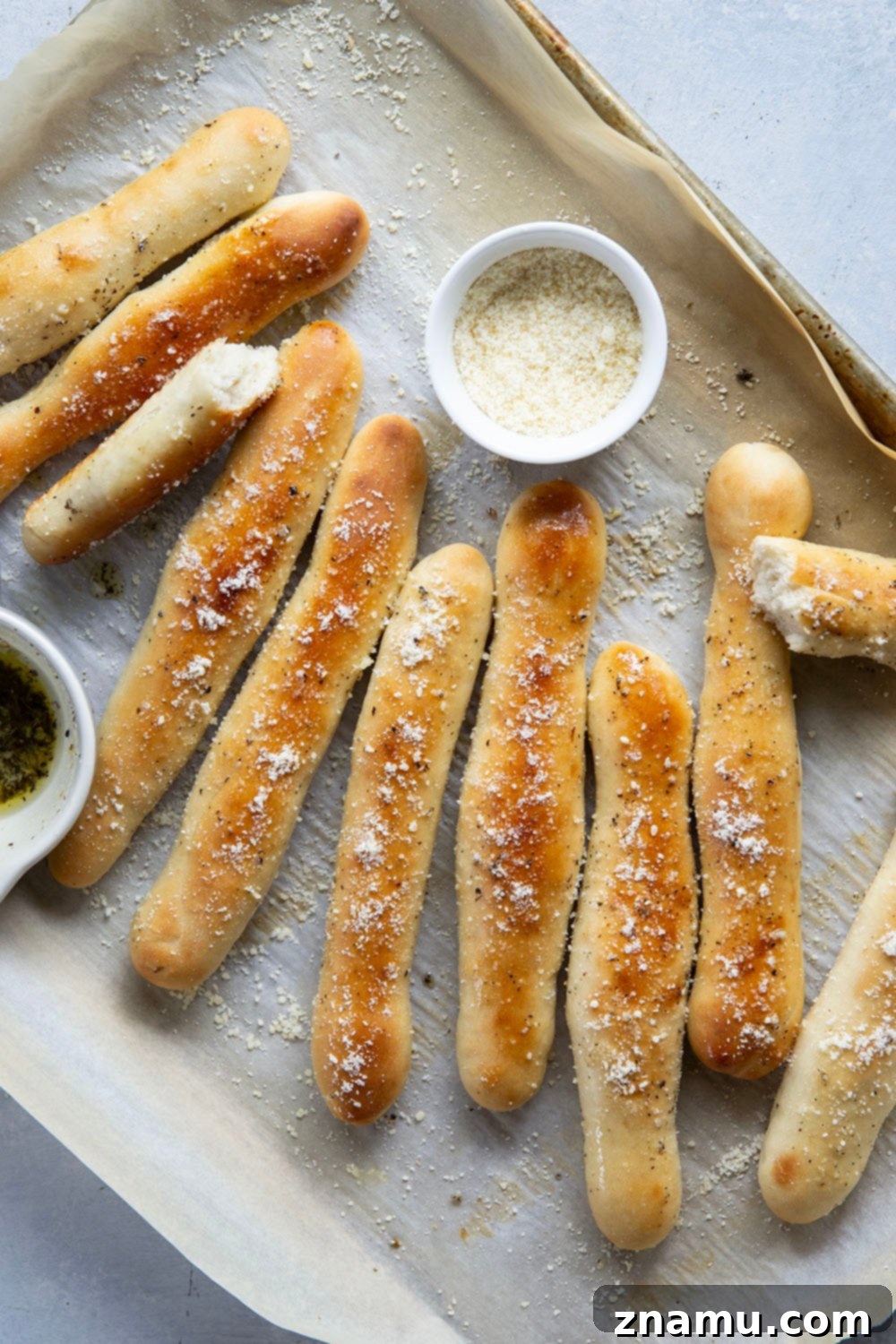 Irresistible Homemade Breadsticks 3 Close-up of golden brown breadsticks coated in melted garlic herb butter and grated Parmesan cheese.