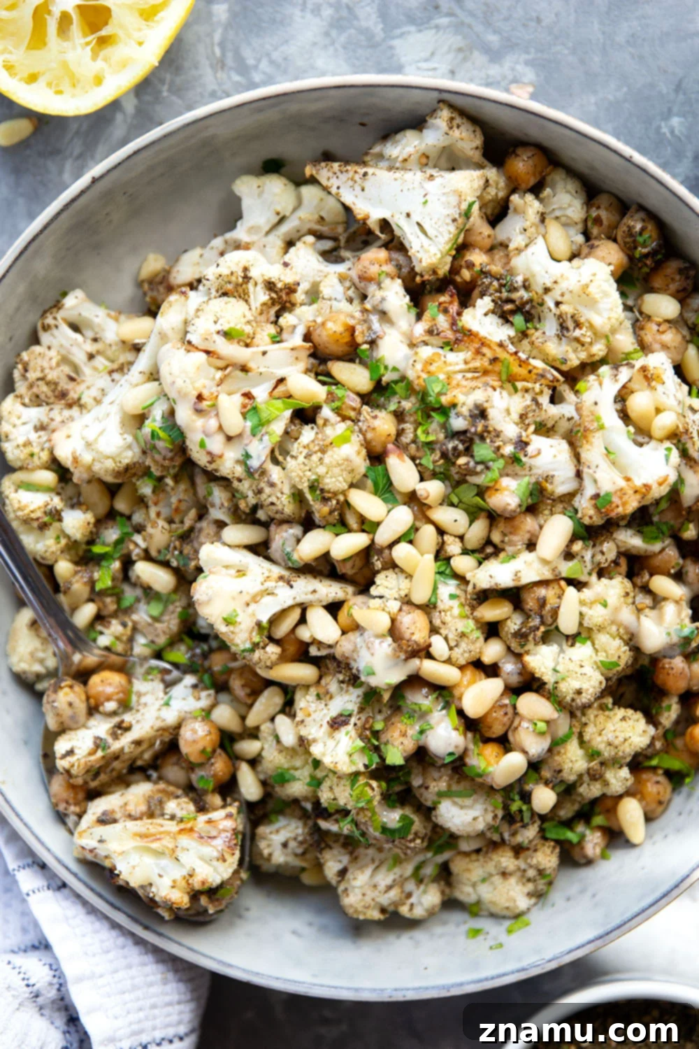 Za'atar Roasted Cauliflower & Chickpea Delight 2 A close-up shot of vibrant Za'atar Roasted Cauliflower and Chickpeas, generously drizzled with tahini, ready to be served.