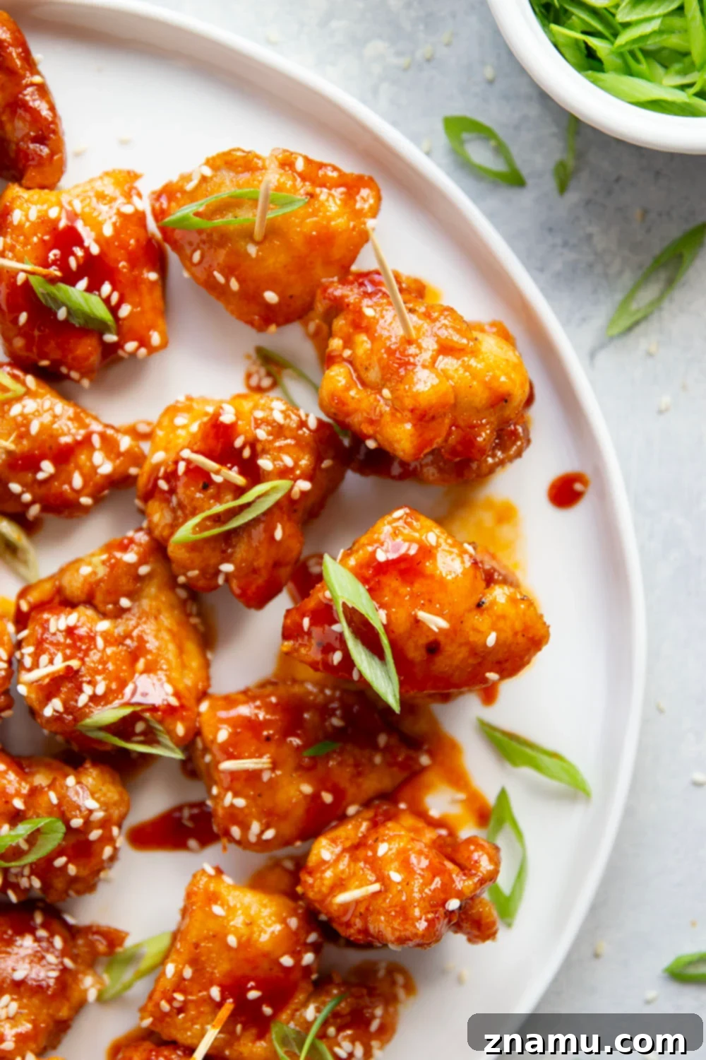 Gochujang Glazed Chicken Bites 3 Close-up of sticky gochujang chicken bites, garnished with sesame seeds and green onions, showcasing their irresistible glaze.