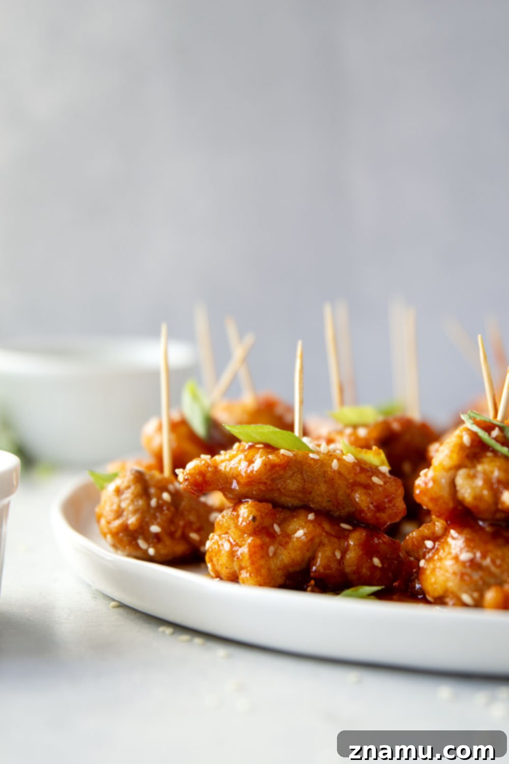 Gochujang Glazed Chicken Bites 5 Hands tossing crispy pan-fried chicken pieces in a rich, sticky gochujang sauce in a skillet.