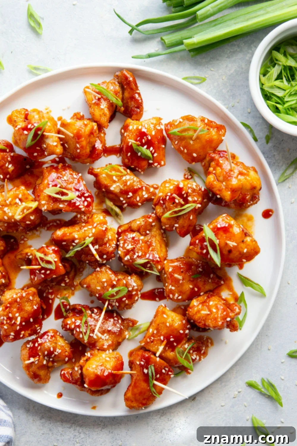 Gochujang Glazed Chicken Bites 6 A serving platter filled with sticky gochujang chicken bites, garnished with sesame seeds and green onions, ready to be enjoyed.