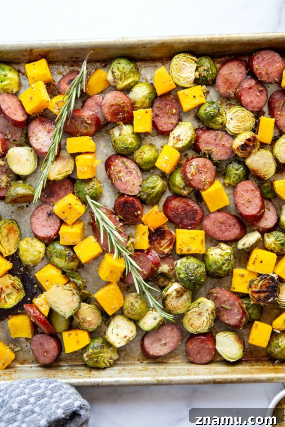 Rustic Sausage and Butternut Sheet Pan Dinner 2 Close-up of roasted sausage and butternut squash coated in rosemary honey mustard sauce on a sheet pan.