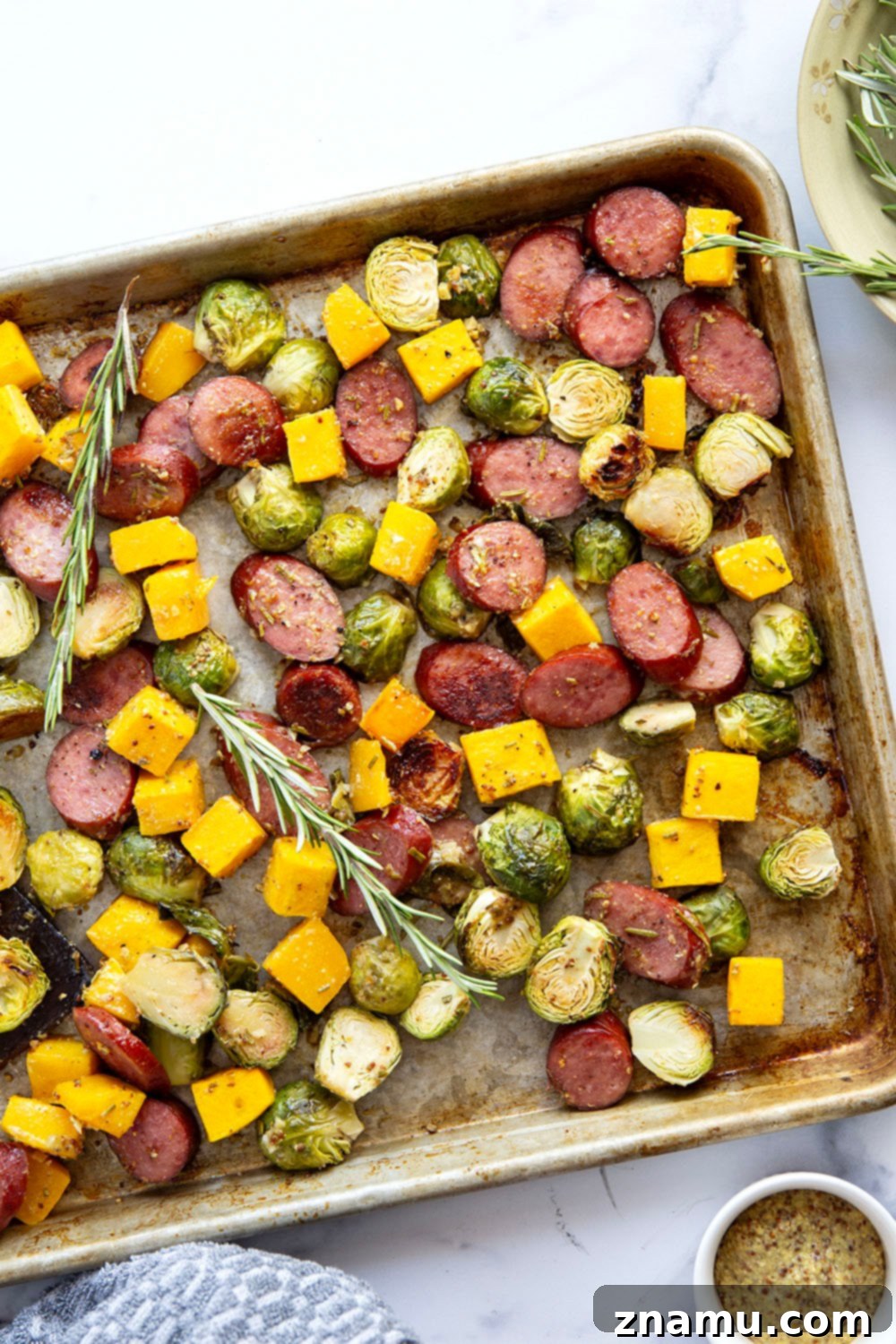 Rustic Sausage and Butternut Sheet Pan Dinner 4 A bowl of rosemary honey mustard sauce next to fresh rosemary sprigs and other sauce ingredients.