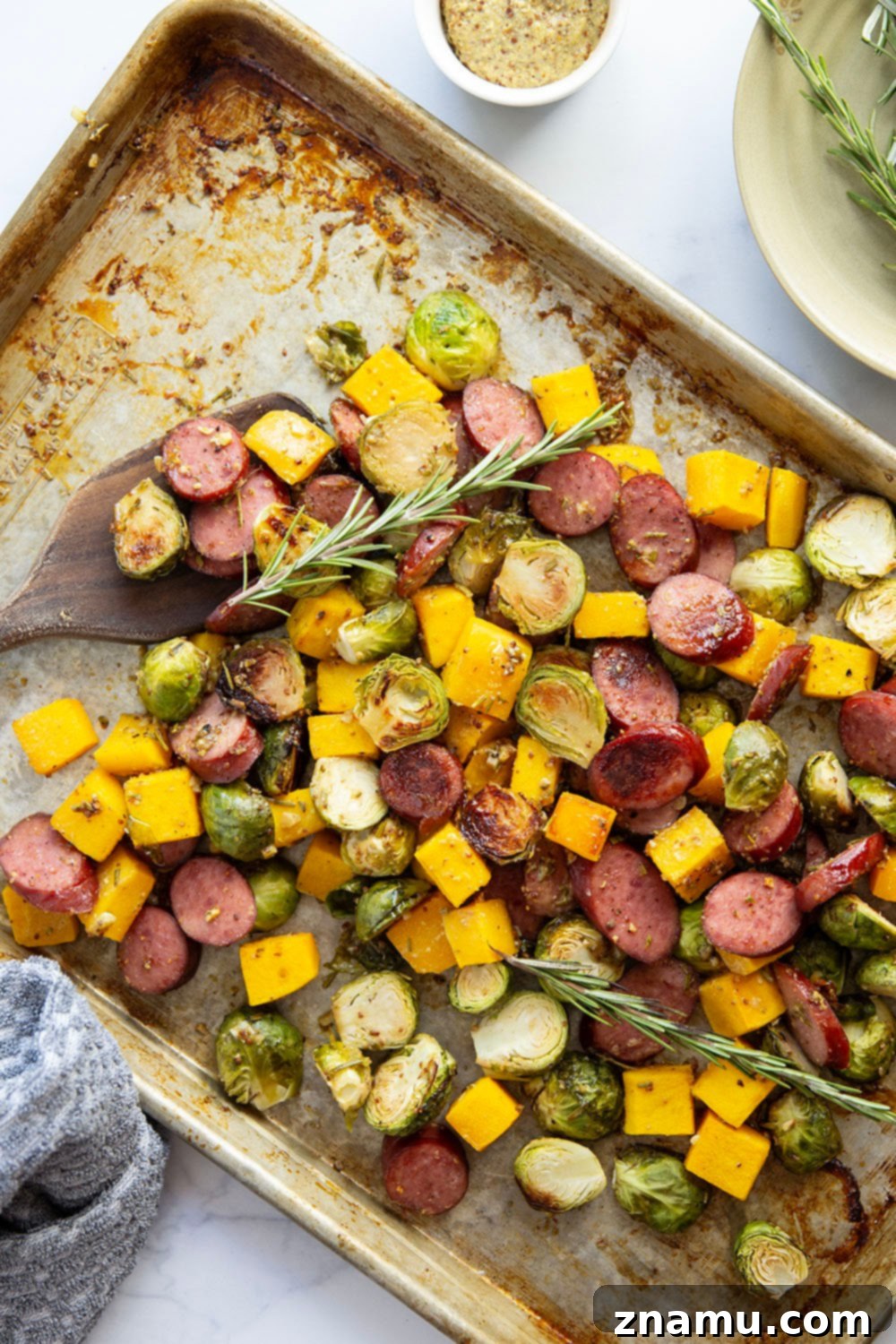 Rustic Sausage and Butternut Sheet Pan Dinner 6 Close-up of a serving of roasted sausage, butternut squash, and brussels sprouts with rosemary honey mustard sauce.