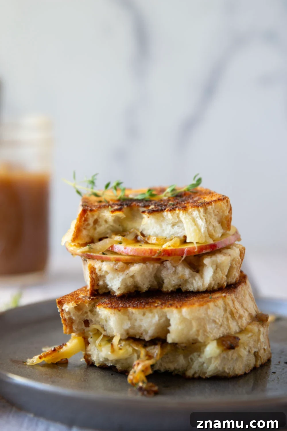 A beautiful cross-section of the apple butter caramelized onion grilled cheese, showing the melted cheese, apples, and onions.