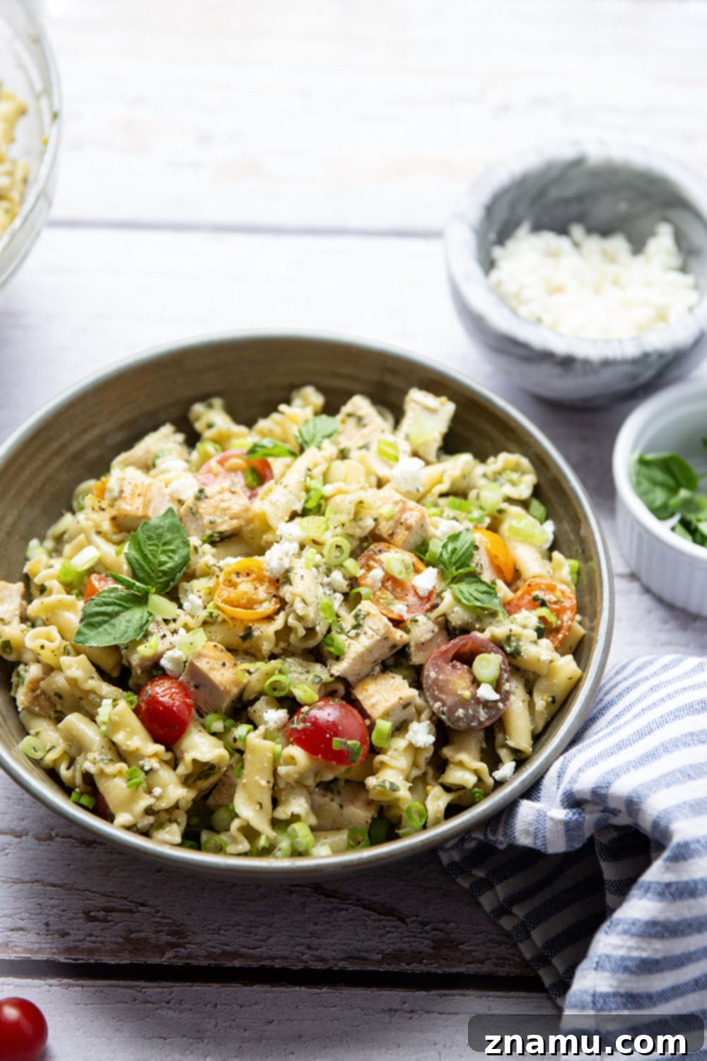 Vibrant Pesto Chicken Pasta Toss 4 Fresh ingredients for chicken pesto pasta salad including pasta, cherry tomatoes, feta cheese, and green onion, ready to be combined.