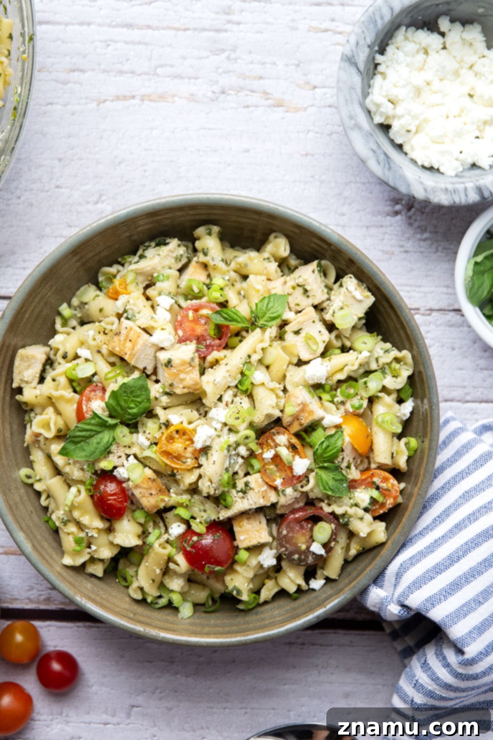 Vibrant Pesto Chicken Pasta Toss 6 Close-up of a vibrant chicken pesto pasta salad in a bowl, showing grilled chicken, cherry tomatoes, and feta.