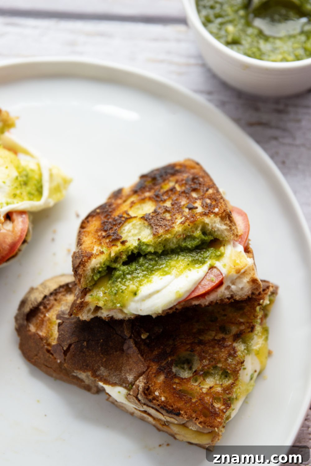 Gourmet Pesto Melt 6 Pesto grilled cheese with visible layers of cheese and tomato, sliced in half