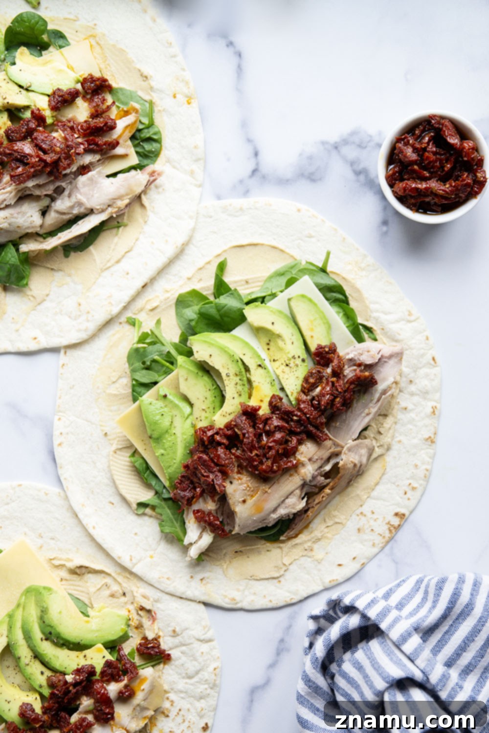 Mediterranean Turkey Hummus Wrap with Sun-Dried Tomatoes 5 A perfectly rolled turkey hummus wrap cut in half, showcasing the layers of ingredients.