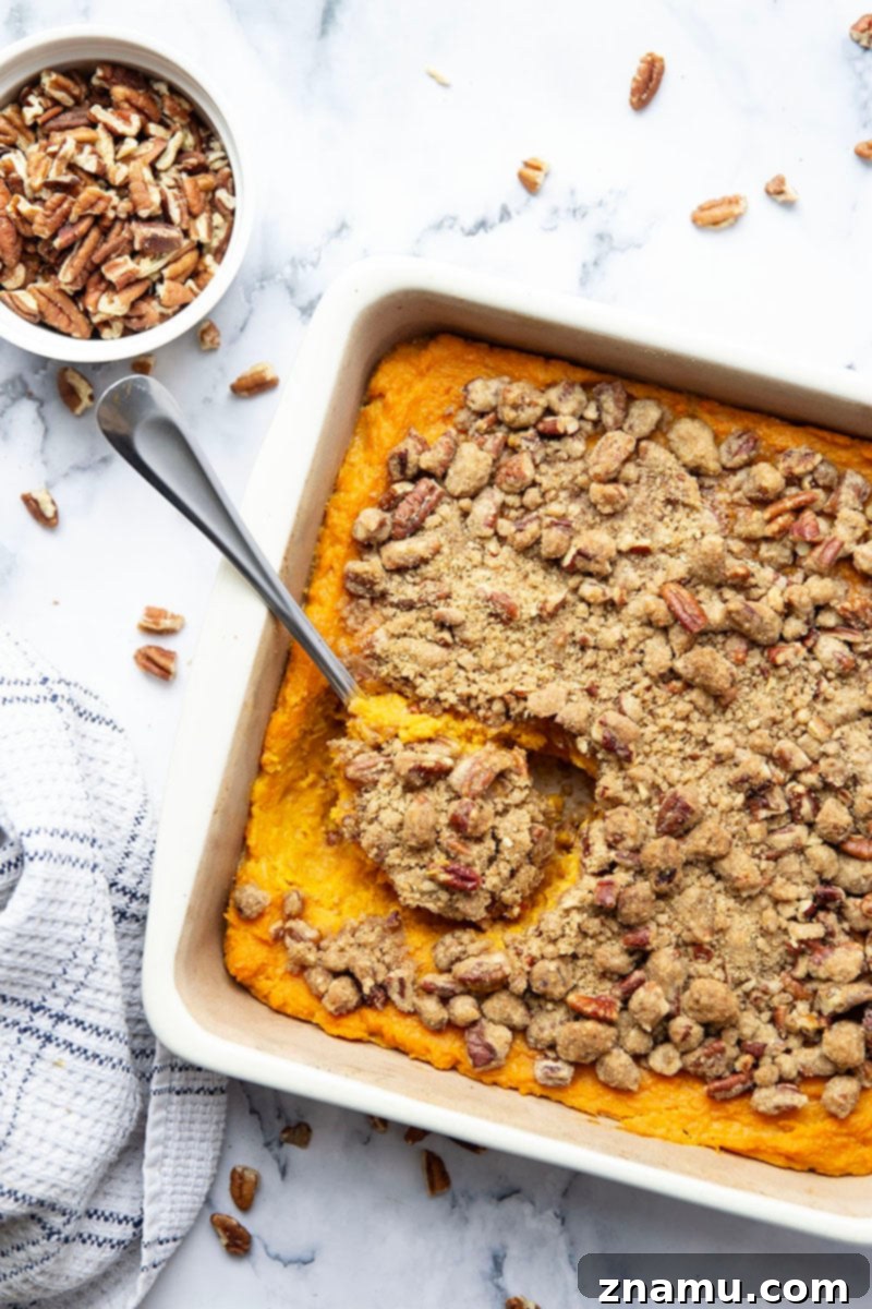 Your Thanksgiving Feast Roadmap 12 A golden-brown Sweet Potato Casserole with Pecan Streusel, freshly baked and ready for serving, in a white baking dish.