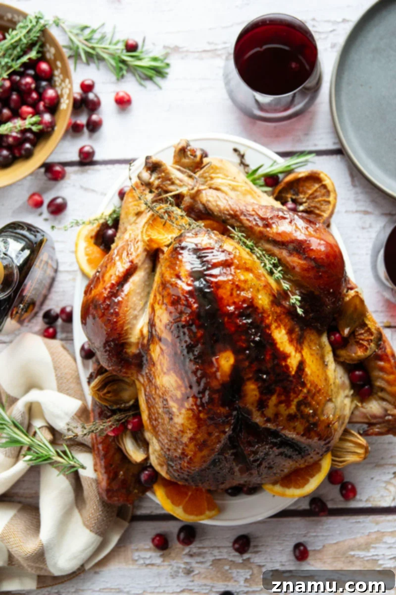 Your Thanksgiving Feast Roadmap 3 A whole roasted maple glazed turkey, golden brown and glistening, garnished with fresh herbs, ready to be carved for a Thanksgiving dinner.