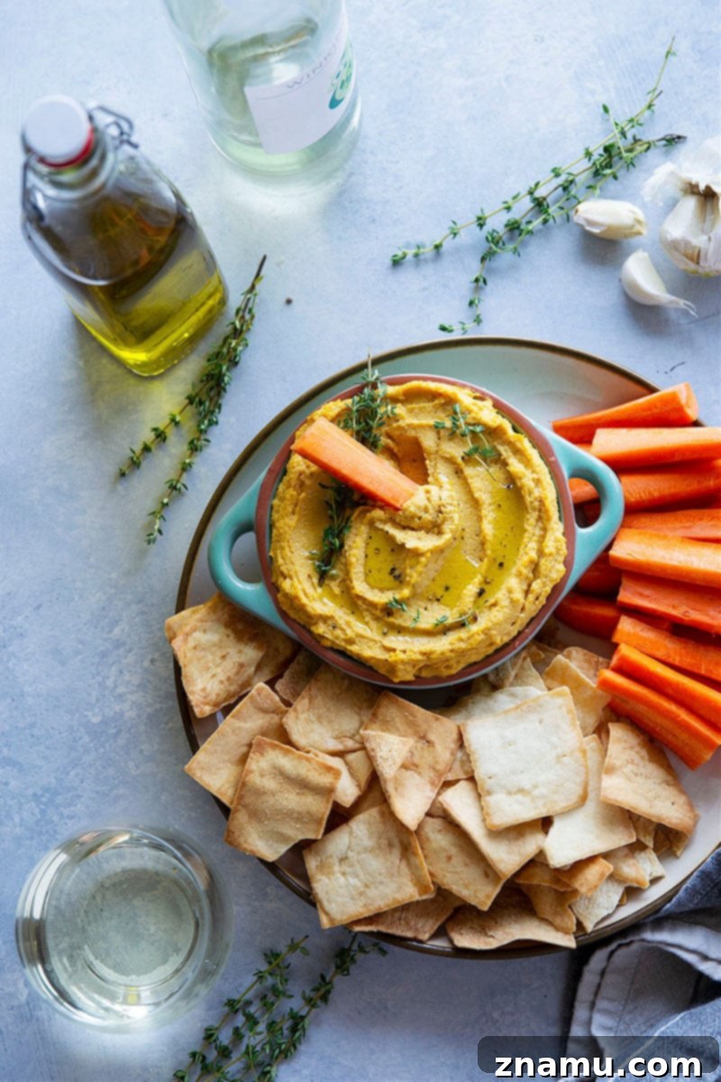Your Thanksgiving Feast Roadmap 8 A bowl of Roasted Garlic Butternut Squash Hummus, garnished with fresh herbs and a drizzle of olive oil, surrounded by pita chips.