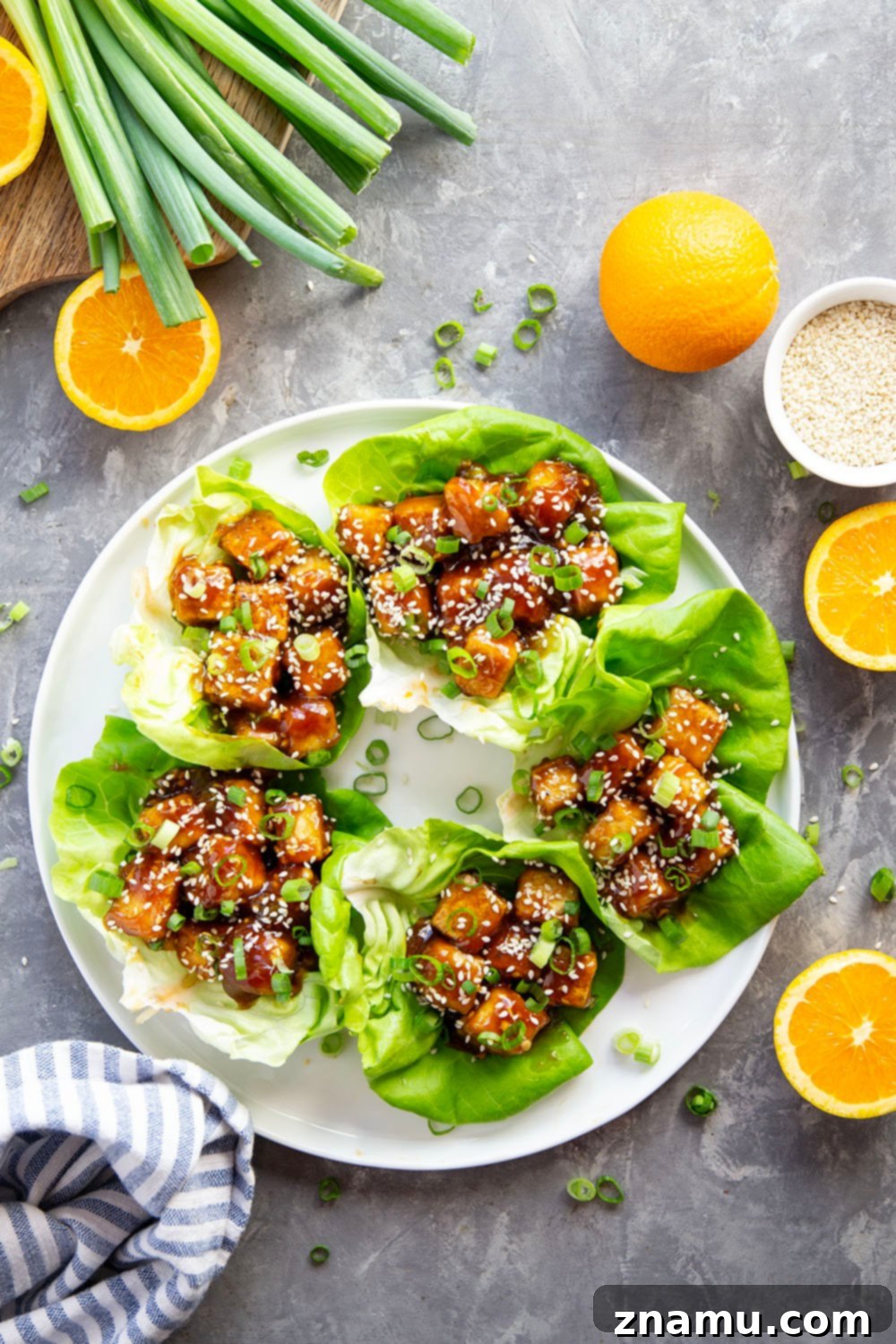 These orange tofu lettuce wraps are tofu's version of orange chicken! Crispy baked tofu is tossed with a sweet homemade orange sauce and then piled in butter lettuce leaves with lots of green onions and sesame seeds on top.