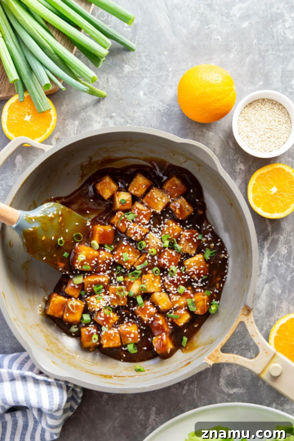 Crispy baked tofu is tossed with a sweet homemade orange sauce and then piled in butter lettuce leaves with lots of green onions and sesame seeds on top.