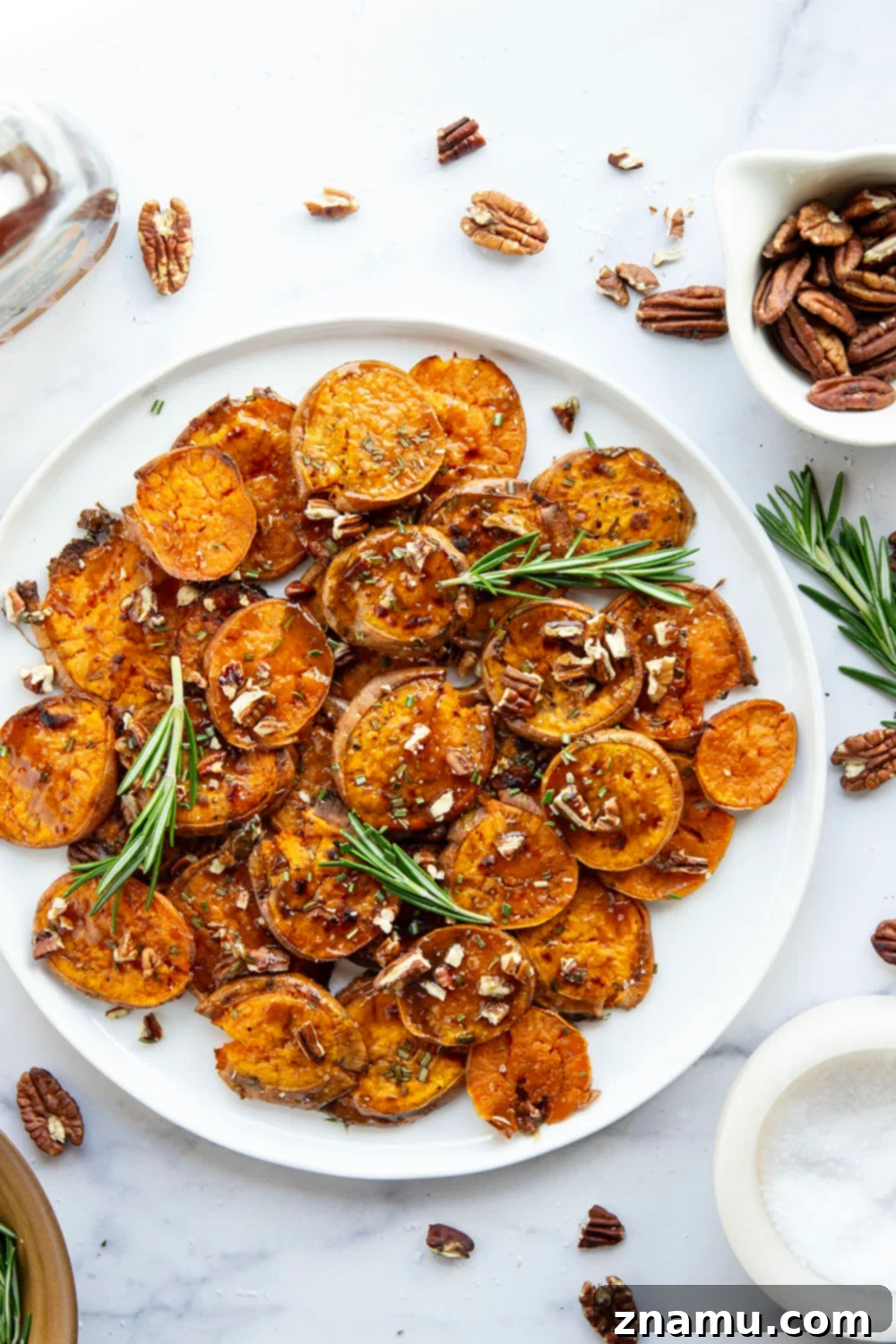 Crispy maple smashed sweet potatoes drizzled with sweet and salty sauce, garnished with rosemary and pecans.
