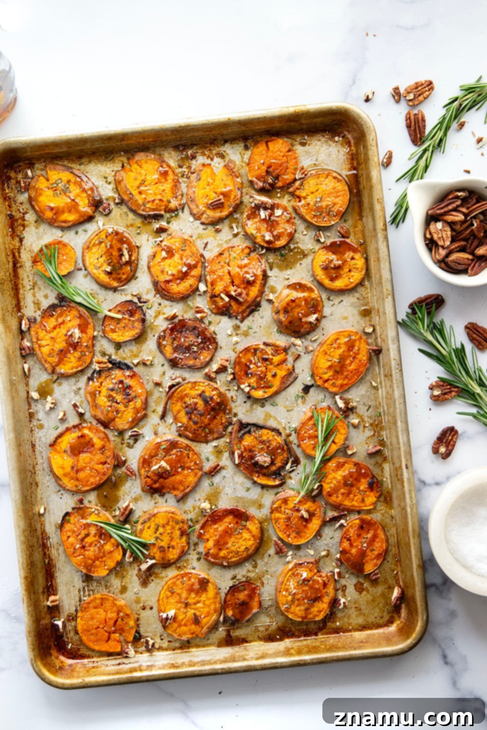 Close-up of golden-brown maple smashed sweet potatoes with fresh rosemary.