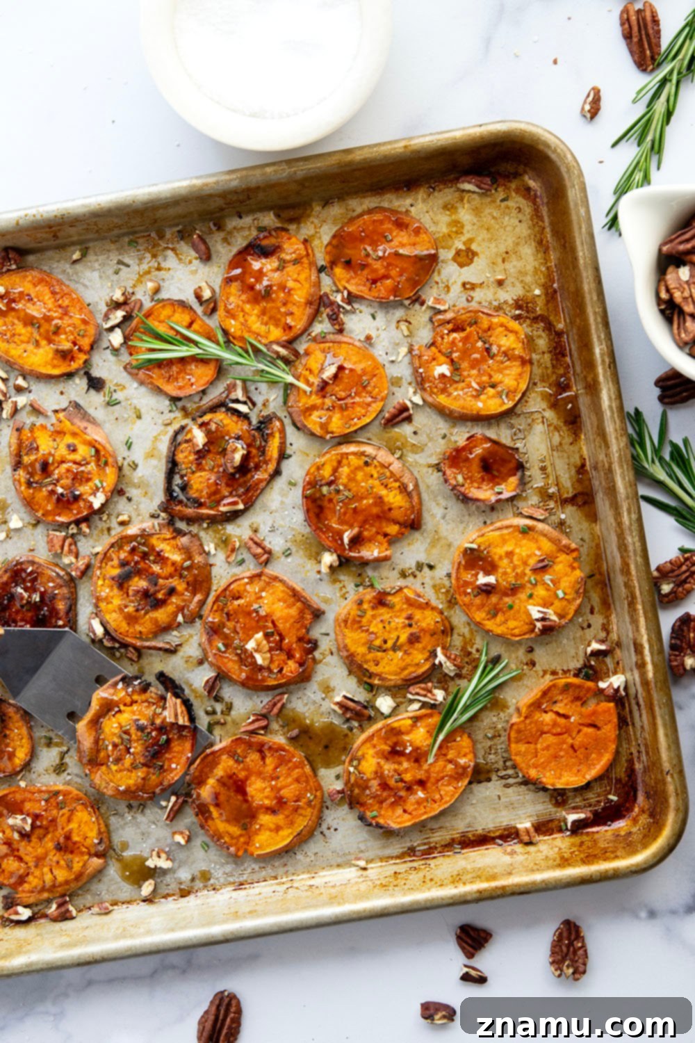 A close-up shot of crispy maple smashed sweet potatoes on a white plate.