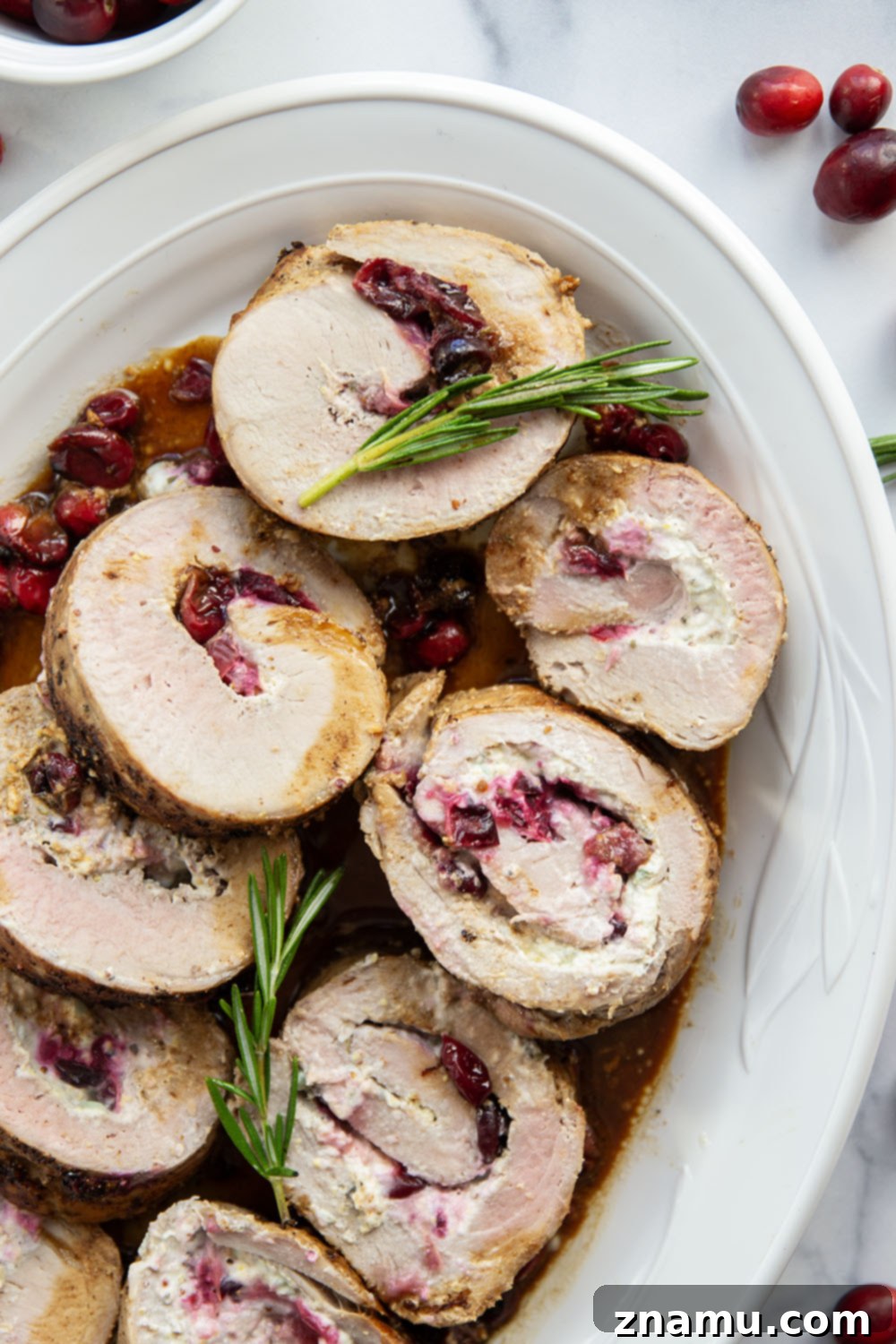 Slices of Goat Cheese Cranberry Stuffed Pork Loin arranged on a platter, ready to serve