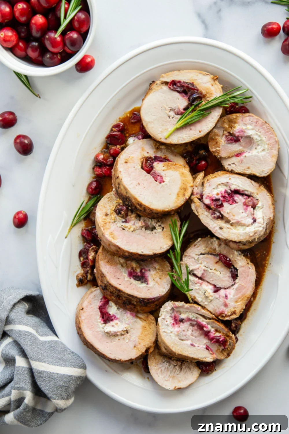 Beautifully plated slices of Goat Cheese Cranberry Stuffed Pork Loin with side dishes