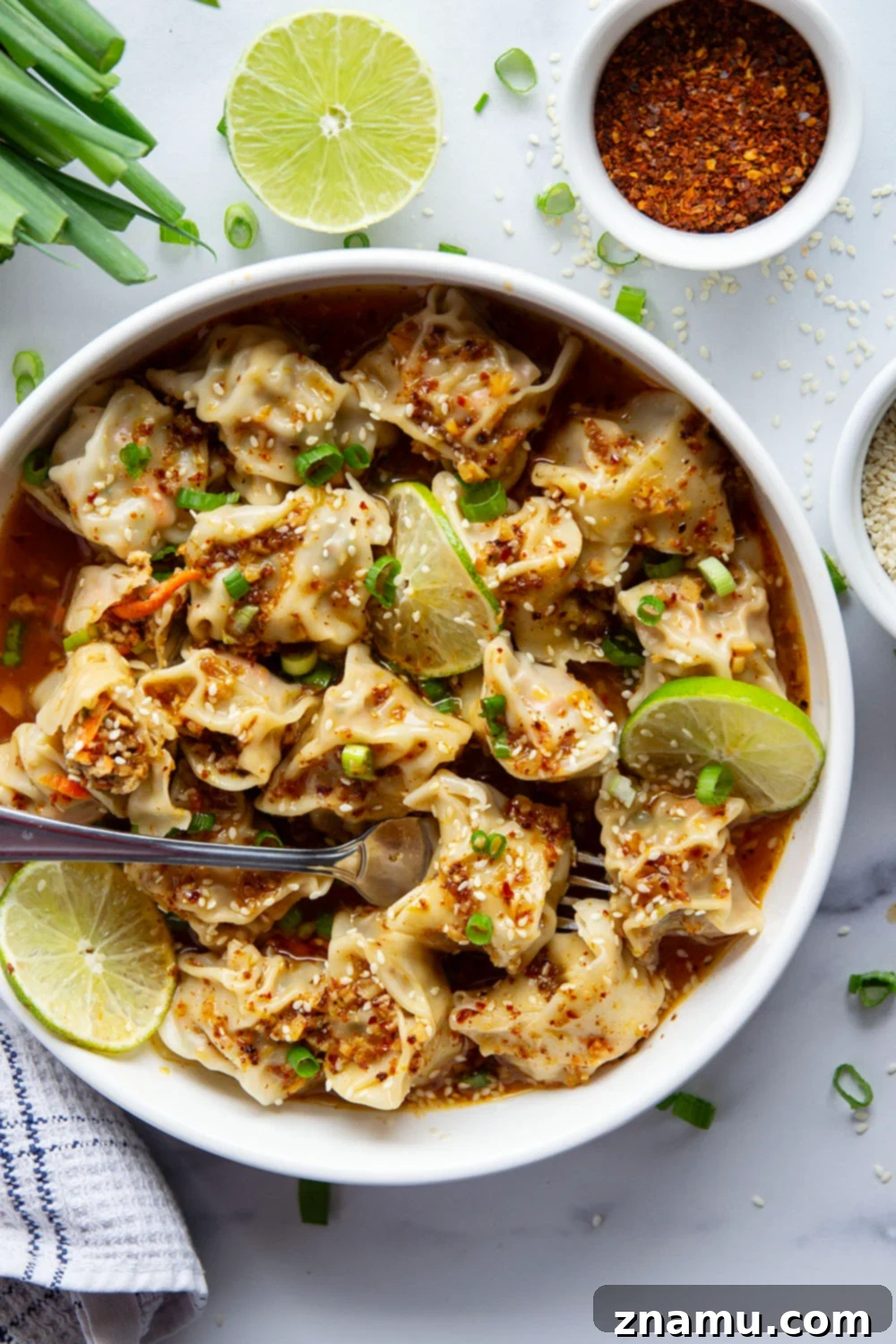 A bowl of spicy chicken wontons with garnishes, ready to be enjoyed