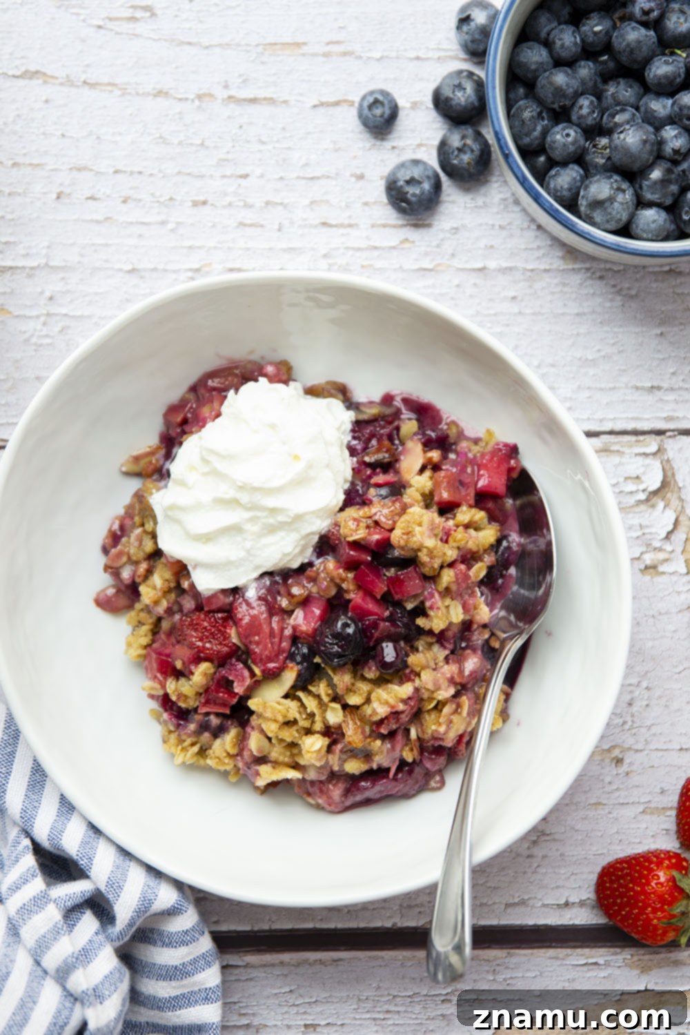 Homestyle Rhubarb Berry Delight 4 A close-up shot of raw Rhubarb Berry Crisp ingredients arranged in a bowl, showcasing fresh rhubarb, strawberries, and blueberries before baking.