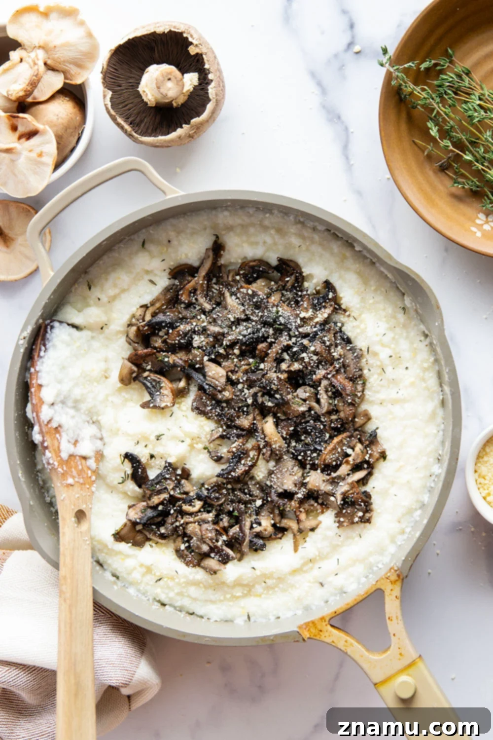 A close-up of creamy grits with wild mushrooms and a golden fried egg, ready to be enjoyed.