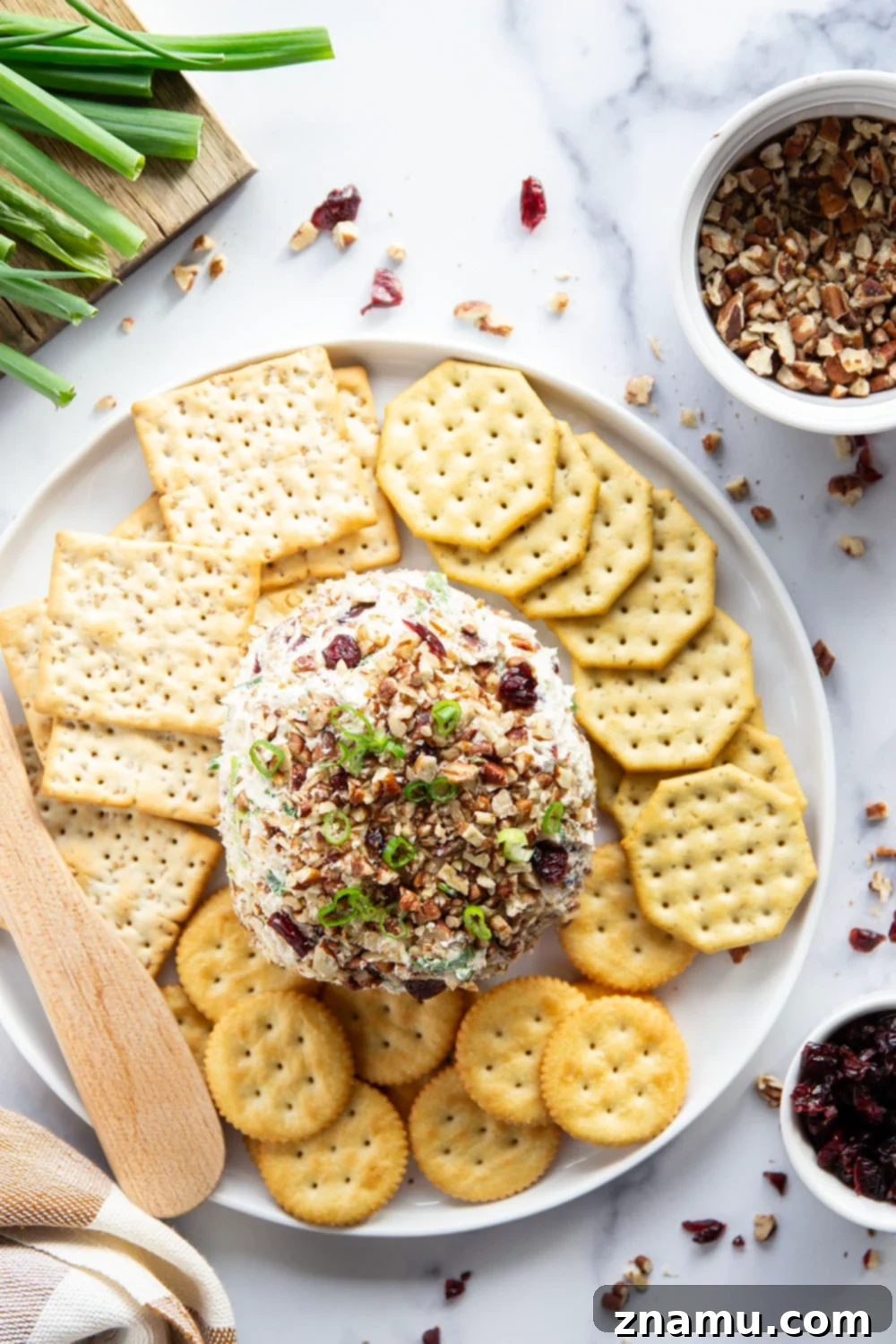 Smoky Cranberry Cheese Delight 4 A festive holiday platter featuring a Smoked Cranberry Cheese Ball, surrounded by various crackers, fresh celery sticks, and red bell pepper slices, ready to be served at a party.