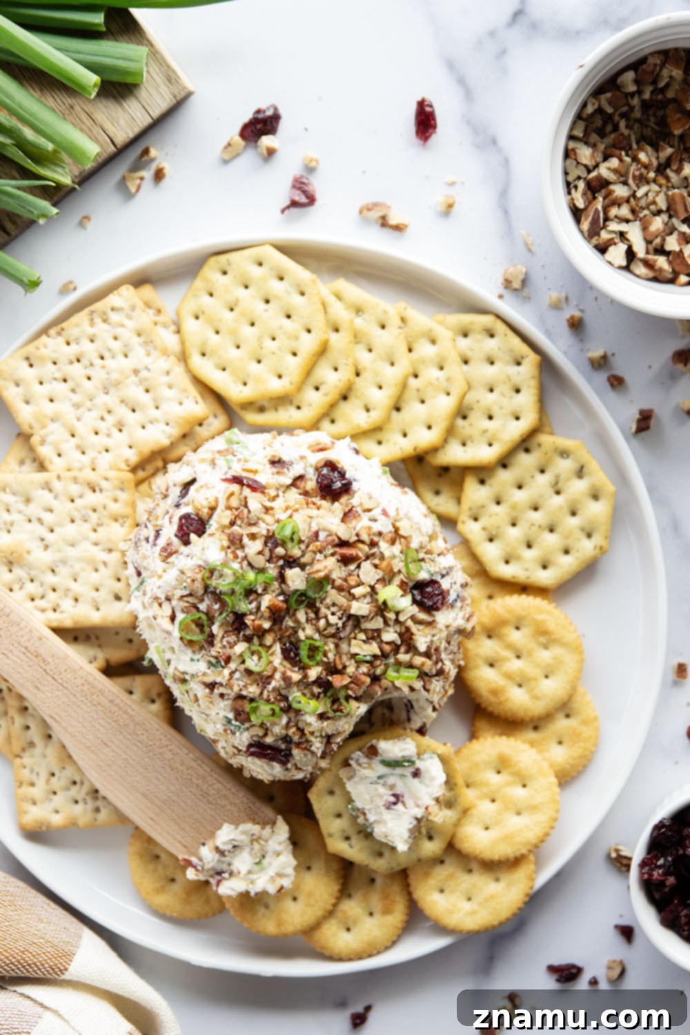 Smoky Cranberry Cheese Delight 5 A bowl of ingredients for the Smoked Cranberry Cheese Ball, showing softened cream cheese, shredded smoked cheddar, Parmesan cheese, sliced green onions, and dried cranberries, ready to be mixed.