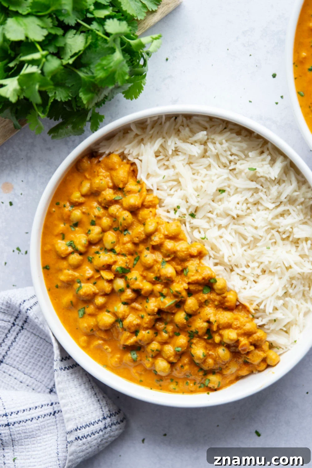 Overhead shot of Instant Pot Butter Chickpeas served with basmati rice, naan bread, and fresh cilantro in a rustic setting.