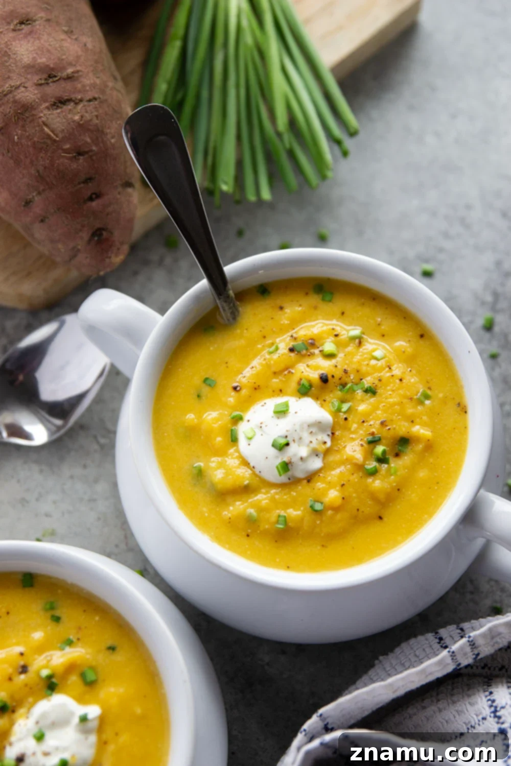 Golden Sweet Potato Leek Bliss 2 A bowl of creamy sweet potato leek soup garnished with fresh chives, beside crusty bread.
