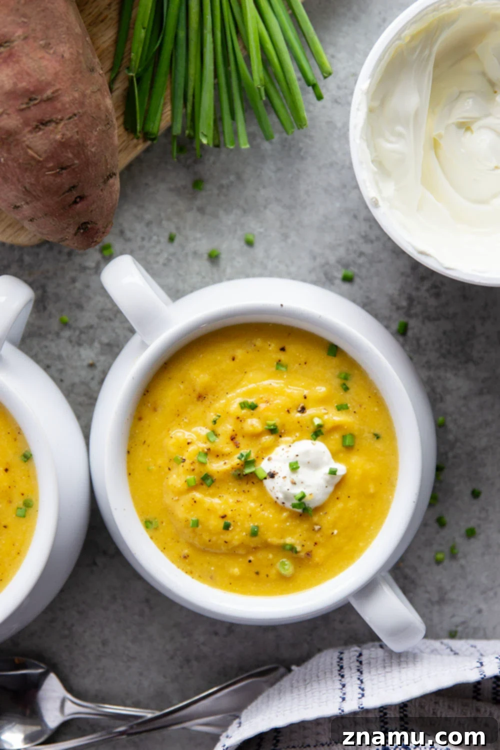 Golden Sweet Potato Leek Bliss 4 A spoonful of creamy sweet potato leek soup being lifted from a white bowl, showing its thick texture.