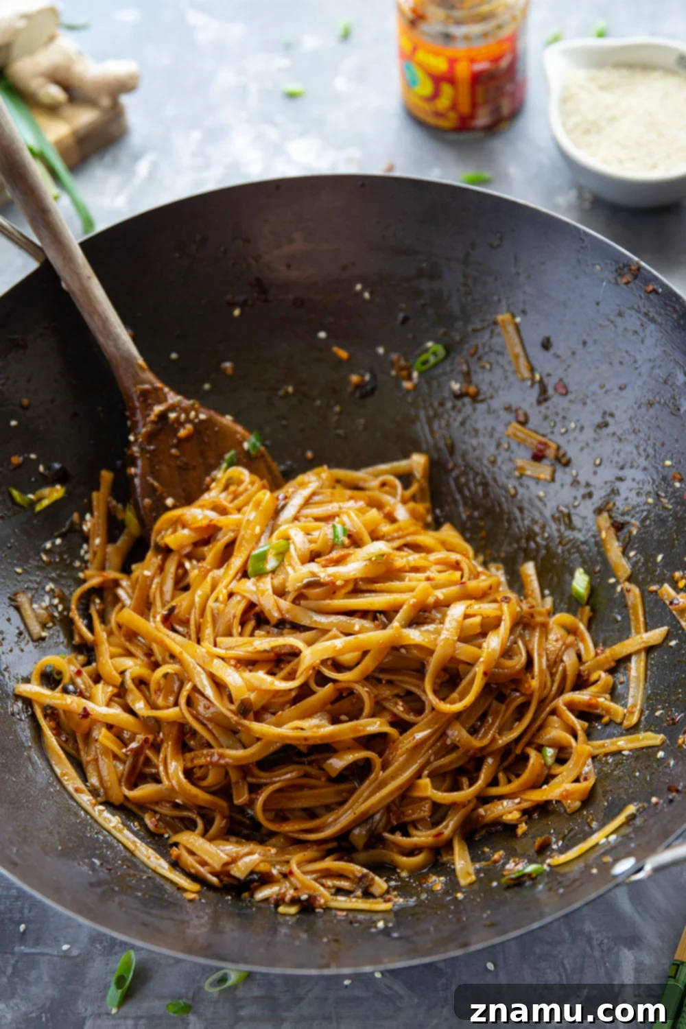 Zingy Ginger Chili Crisp Noodles 3 Close-up of a pan filled with Ginger Chili Crisp Noodles, highlighting the glossy sauce, tender noodles, and vibrant green onions. This spicy and flavorful dish is a quick and satisfying meal option.