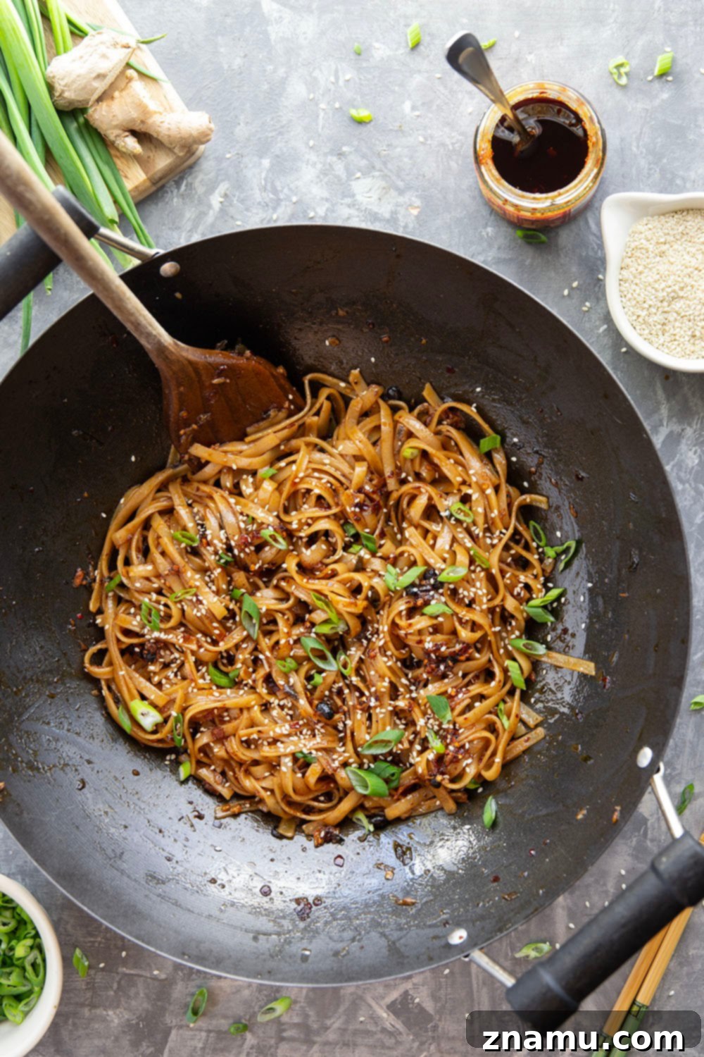 Zingy Ginger Chili Crisp Noodles 6 A chef's hand tossing Ginger Chili Crisp Noodles in a wok, showing the process of coating the noodles evenly with the flavorful sauce. Emphasizes the dynamic and quick cooking method for these spicy noodles.