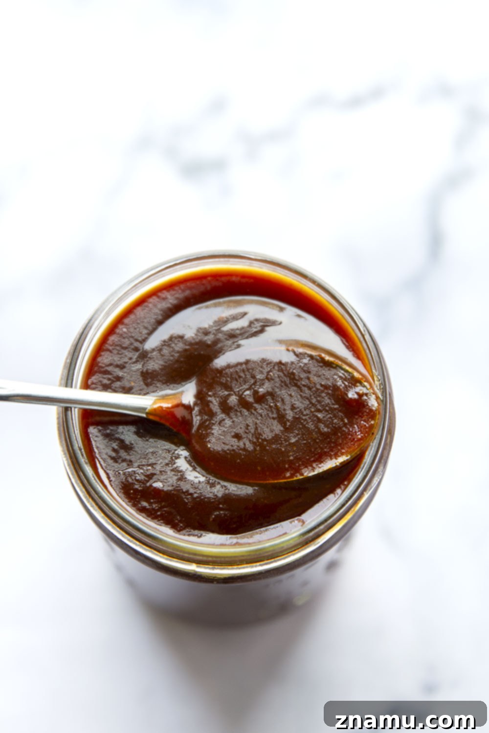 Freshly made homemade BBQ sauce in a clear jar, ready for use on grilled meats or as a dipping sauce.