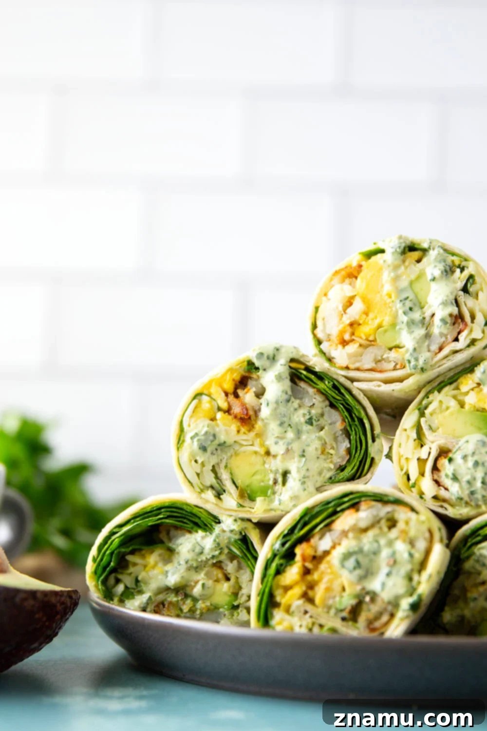 Vibrant Green Goddess Breakfast Burritos 5 A hand holding a perfectly rolled Green Goddess Breakfast Burrito, showcasing its appealing cross-section.