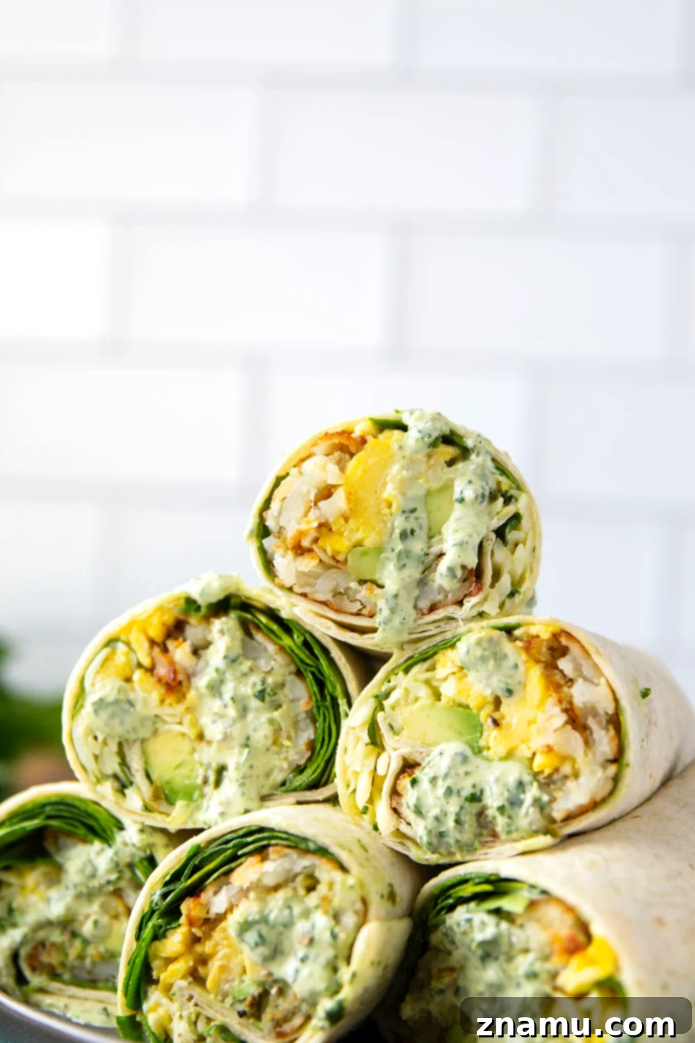 Vibrant Green Goddess Breakfast Burritos 6 Cross-section of a Green Goddess Breakfast Burrito, revealing layers of ingredients and sauce.