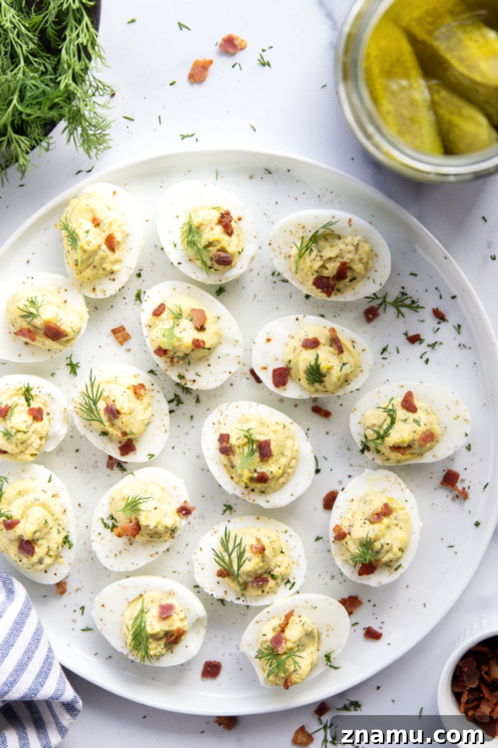 Zesty Bacon Dill Pickle Deviled Eggs 6 Freshly prepared dill pickle deviled eggs on a white plate, ready to be served.