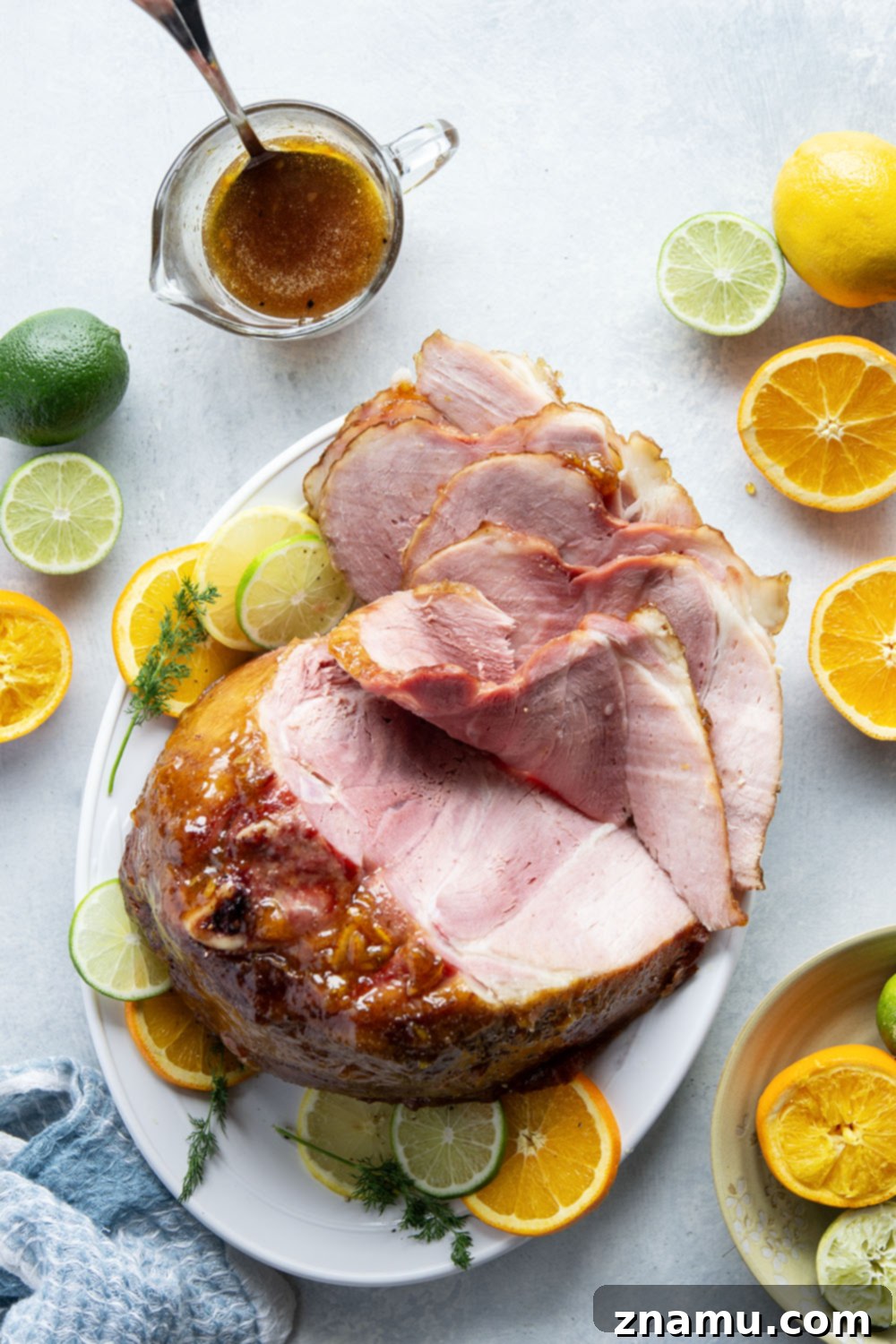 Sweet and Tangy Glazed Ham 5 Various fresh citrus fruits including oranges, lemons, and limes, alongside a jar of honey and a spiral-sliced ham, ready for preparation of the glaze.