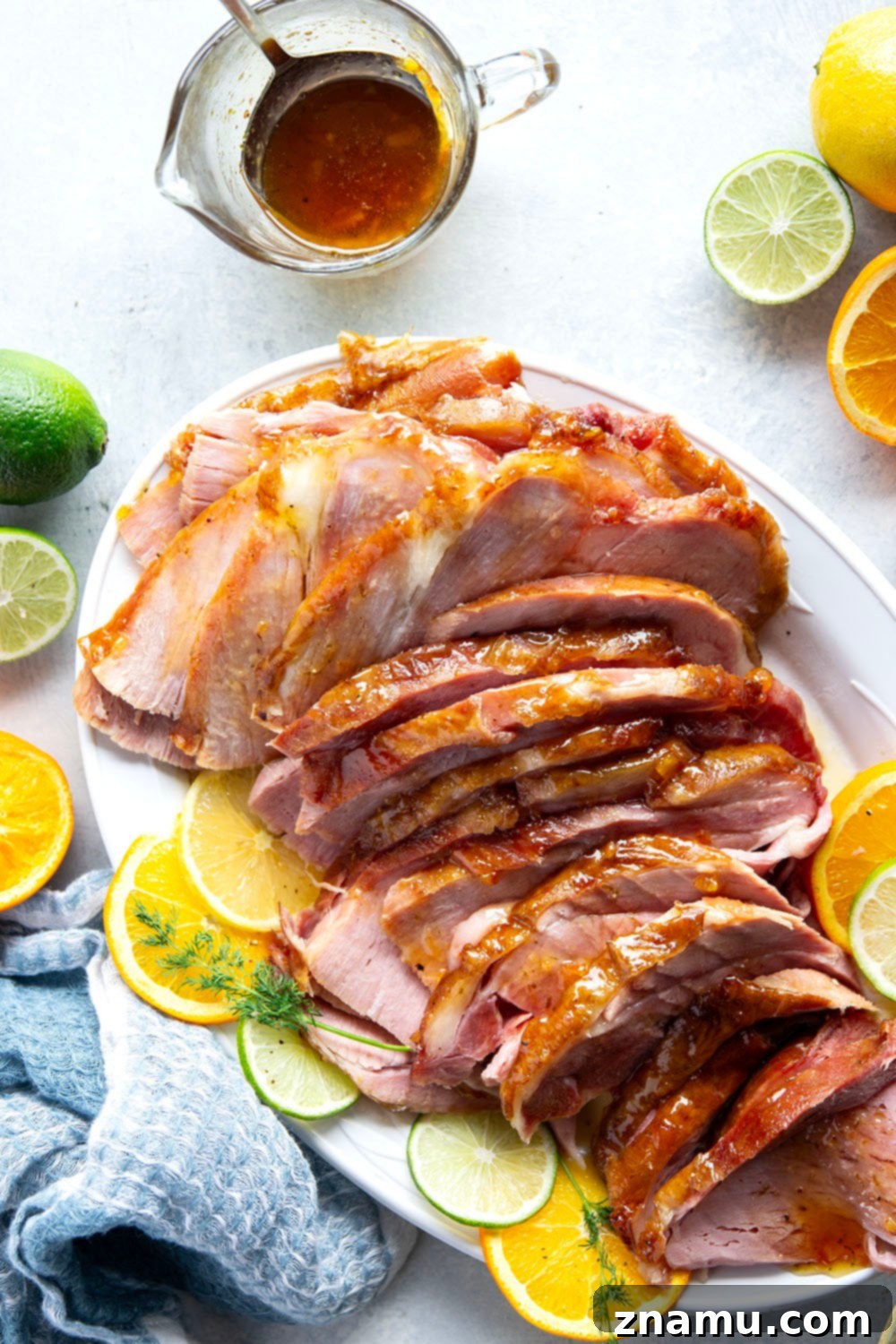 Sweet and Tangy Glazed Ham 6 A large platter filled with beautifully carved honey citrus glazed ham slices, garnished with fresh citrus wedges and herbs, ready for serving guests.