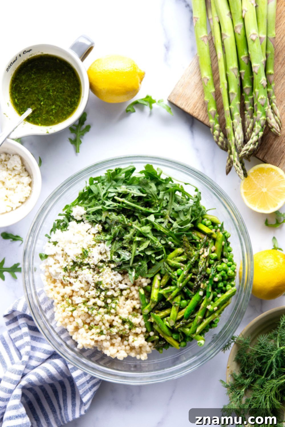 Spring Asparagus Couscous Salad with Zesty Dill Vinaigrette 3 Close-up of a colorful Asparagus Couscous Salad showcasing green asparagus, peas, and pearl couscous, ready to be enjoyed.
